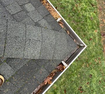 Clogged gutter full of leaves, dirt, and moss on residential roof in Keizer, Oregon – before professional cleaning by Dou-Glass